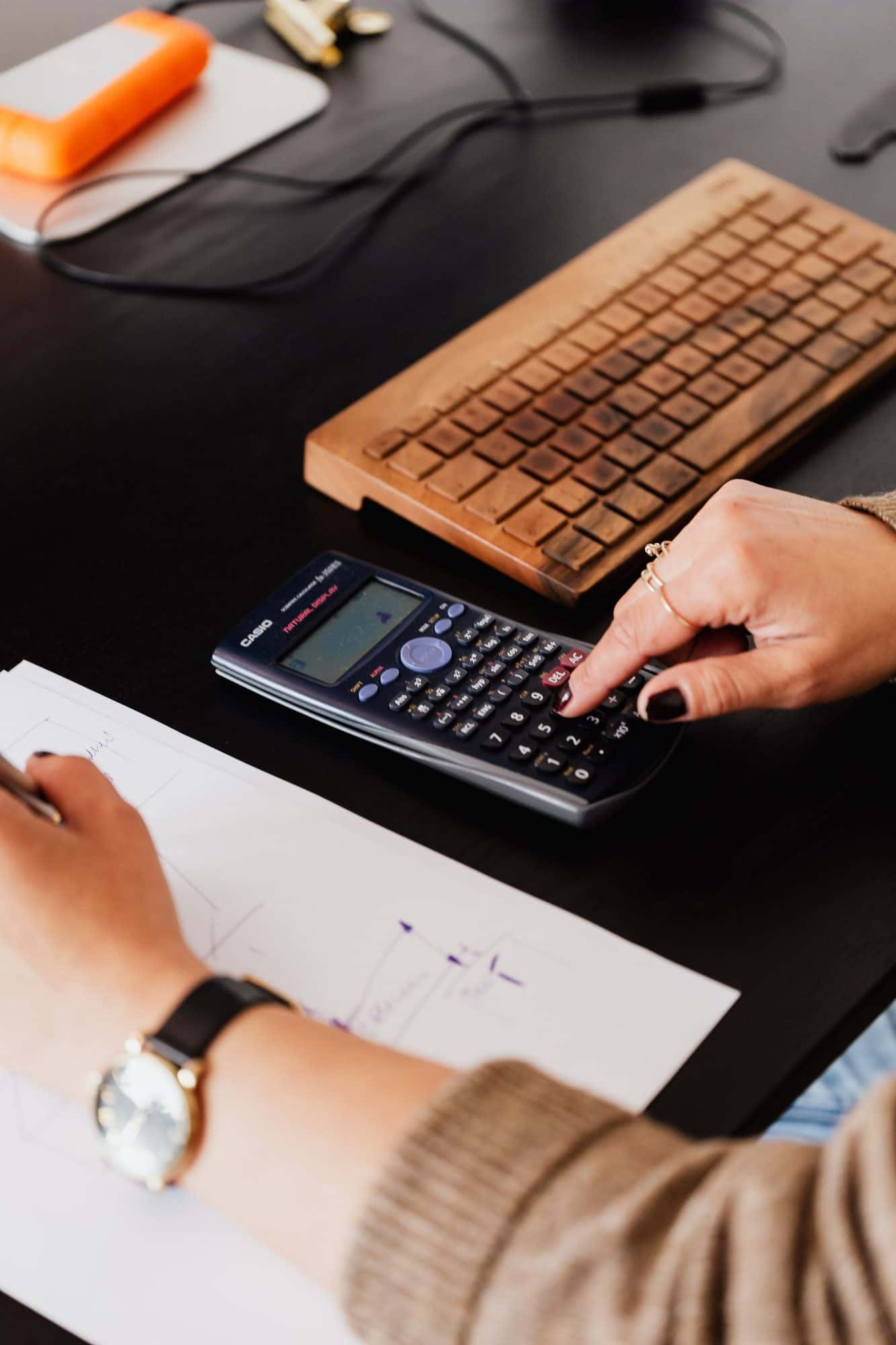 Hands working through figures with a calculator and notes